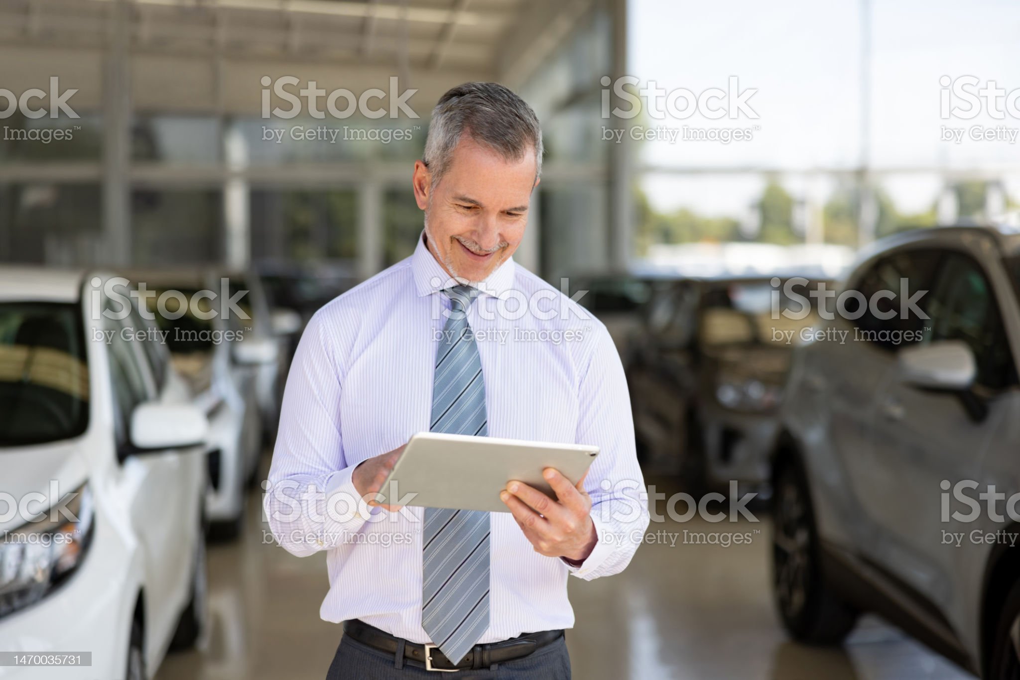 Portrait of a successful car salesperson working at the dealership using a tablet