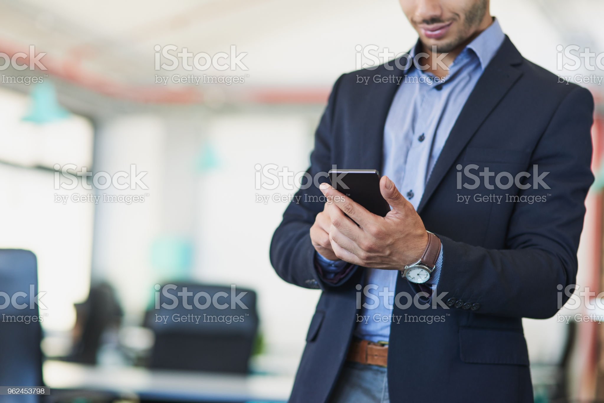 Closeup shot of an unrecognizable businessman using a cellphone in an office